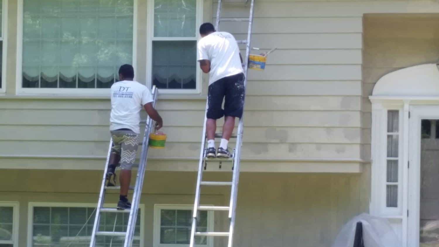 Two DT painters on ladders repainting house siding