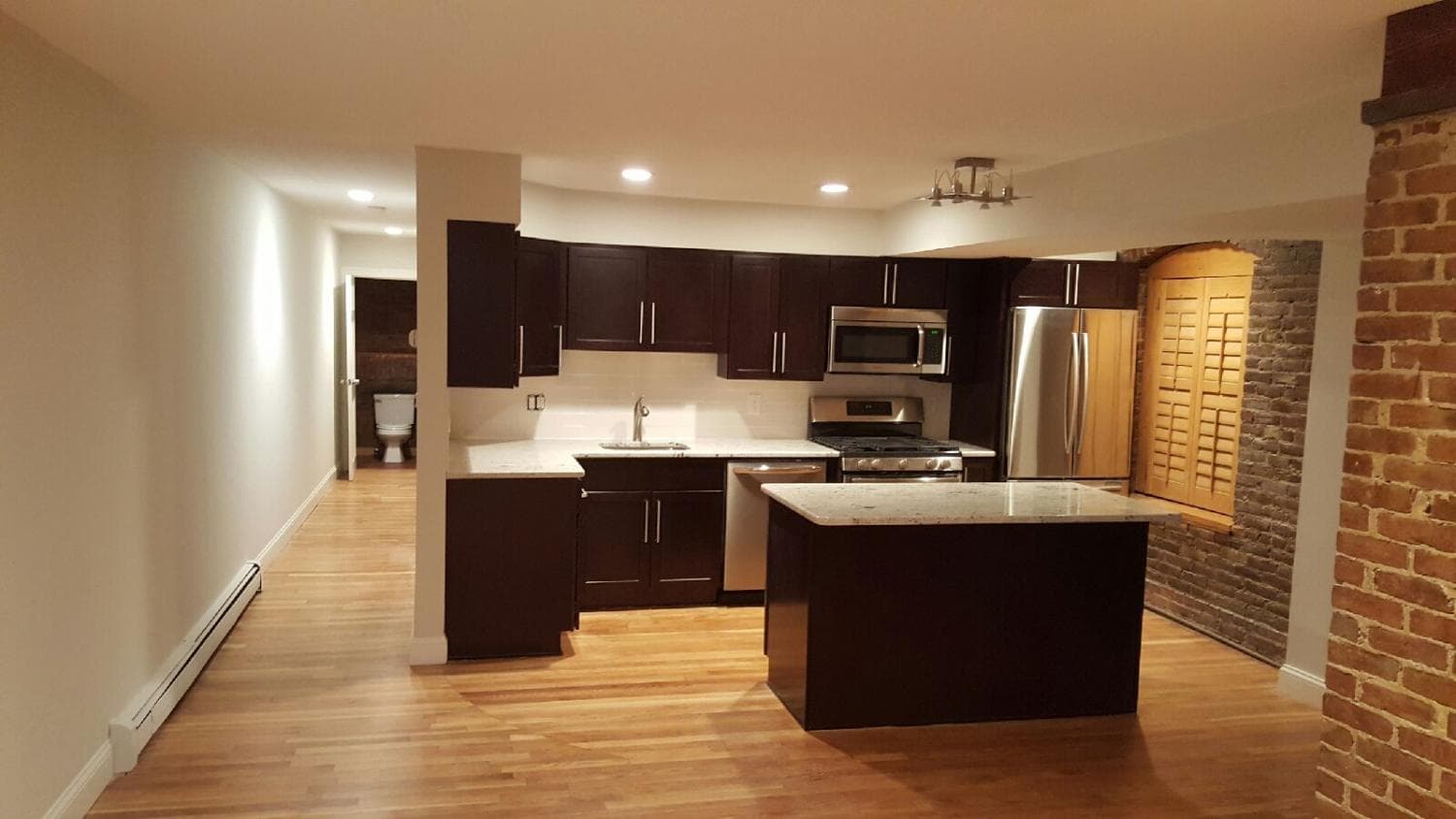 Kitchen with dark cabinets, island and brick wall