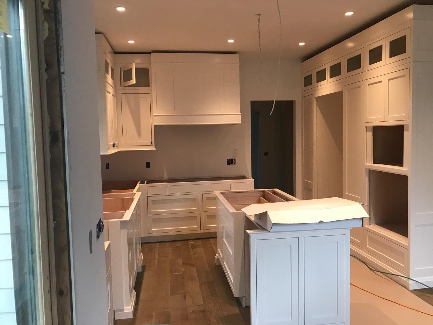 White kitchen cabinets and an island being installed in a remodeled kitchen