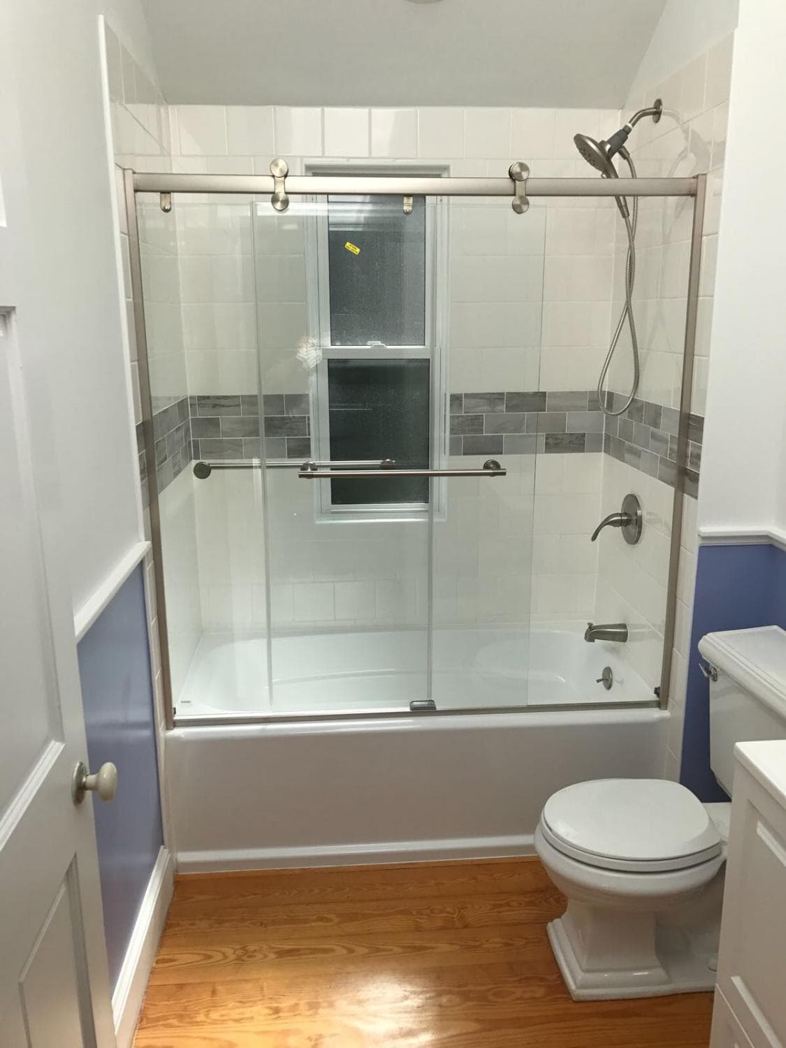 Remodeled bathroom with a glass shower door and tile surround