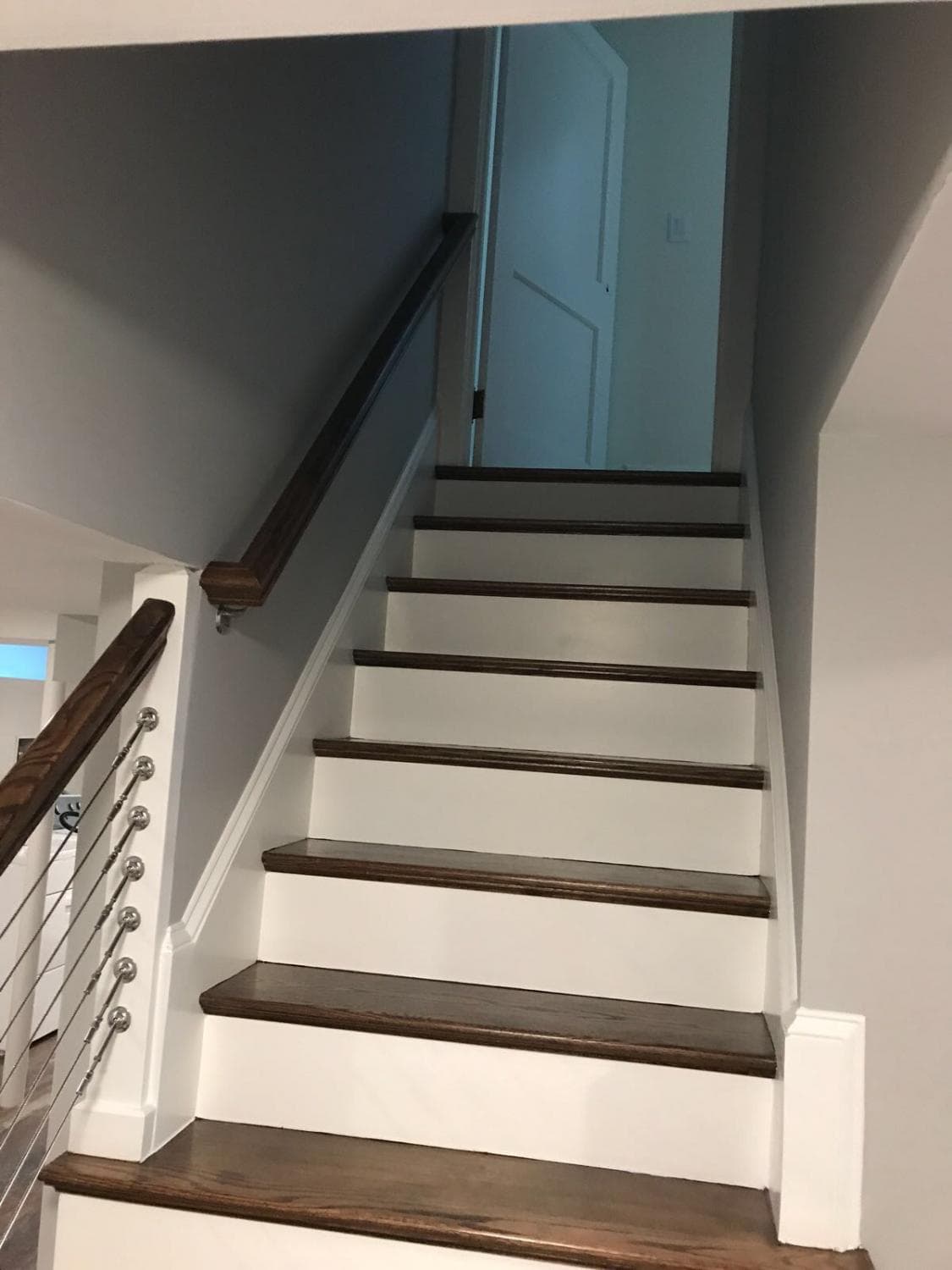 Finished basement stairs with white risers and wood treads