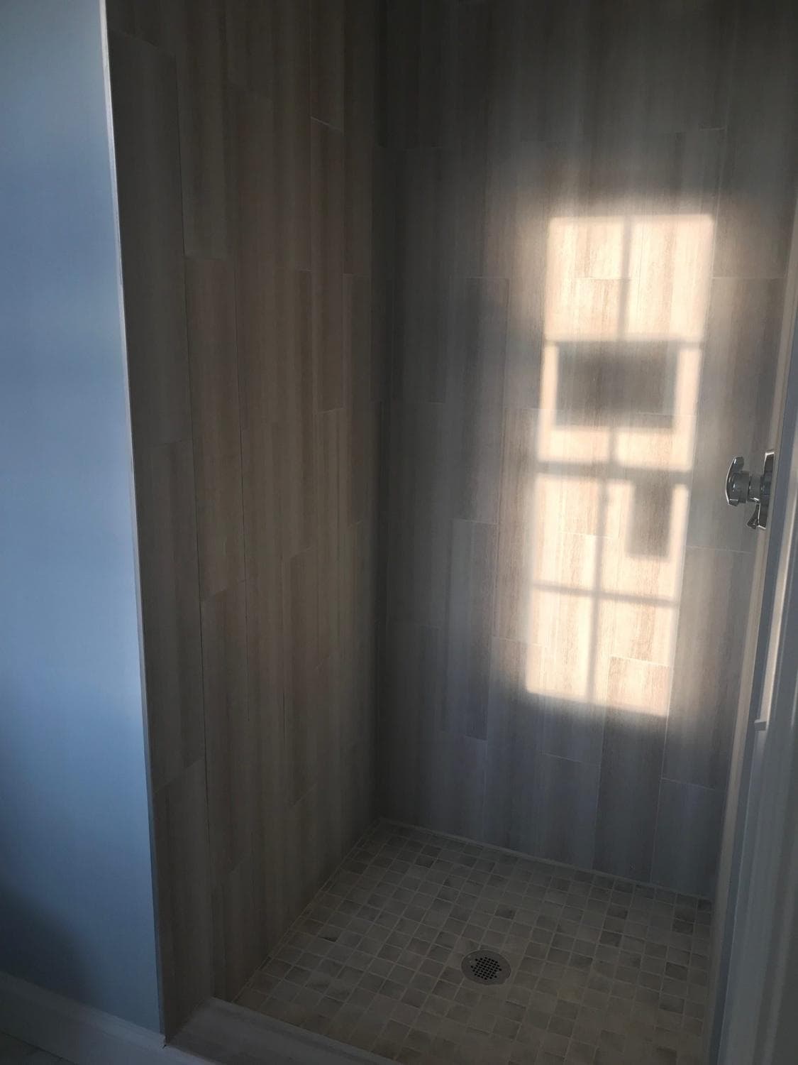 Tile shower with wood-look plank walls and mosaic floor