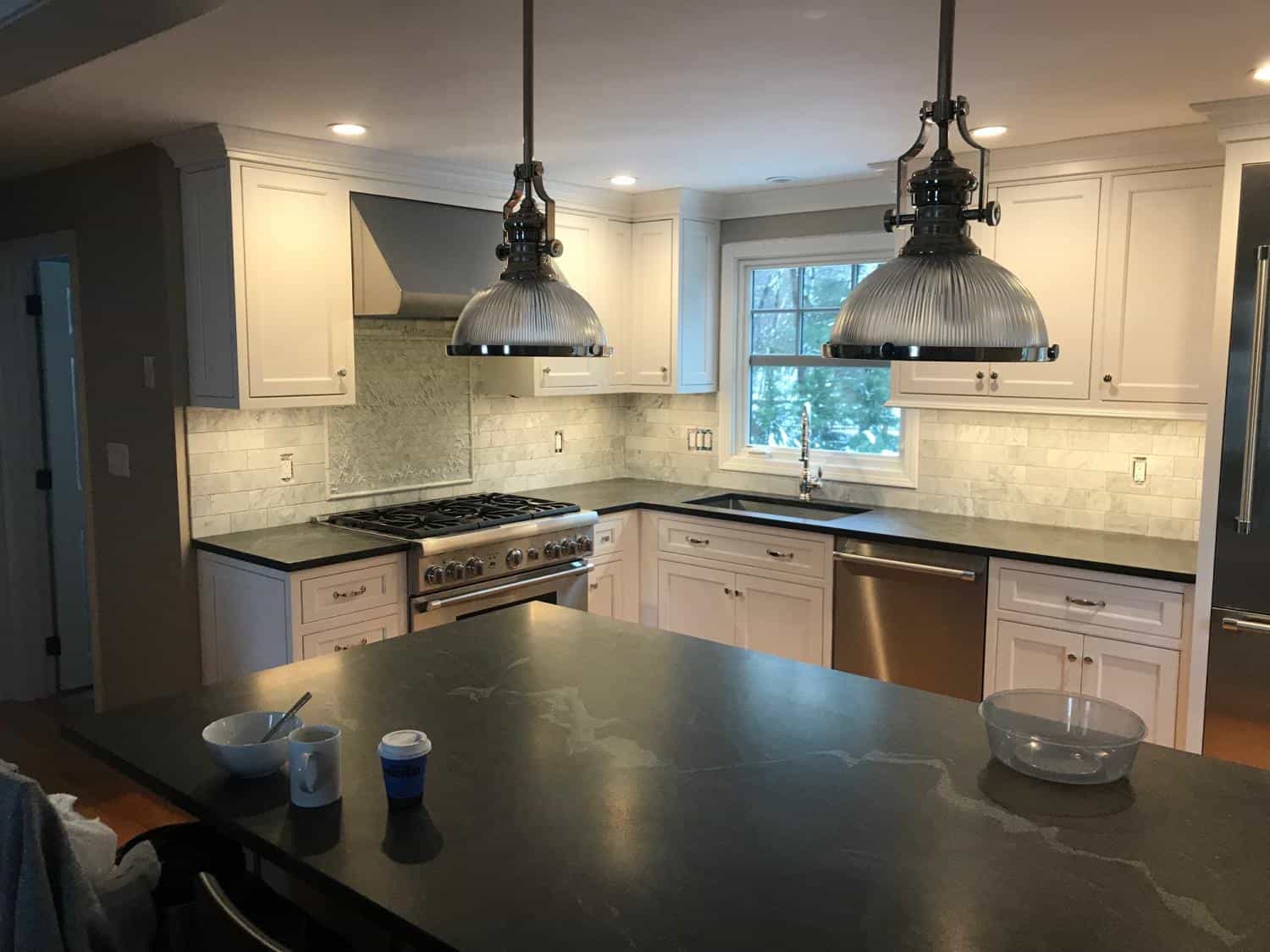 White kitchen with dark counters and big pendant lights
