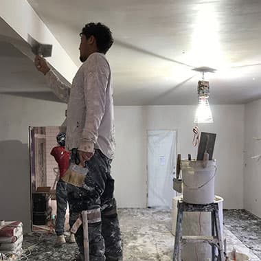 DT crew member plastering a ceiling