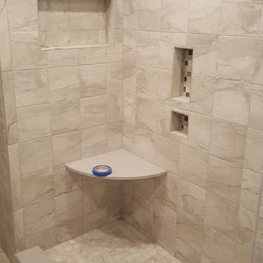 Tile shower with a corner seat and recessed niches